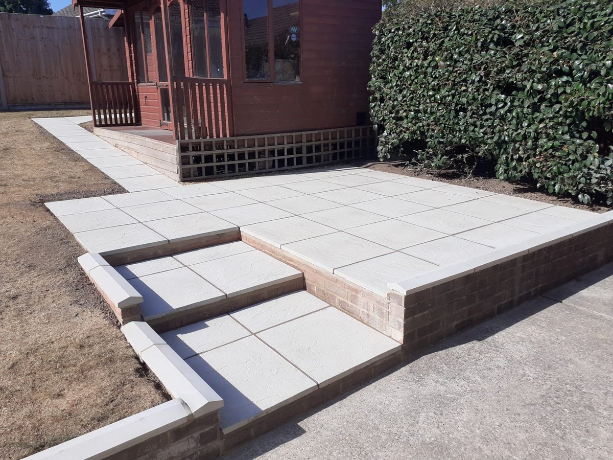 Modern patio with concrete pavers and built-in seating steps in front of brick building